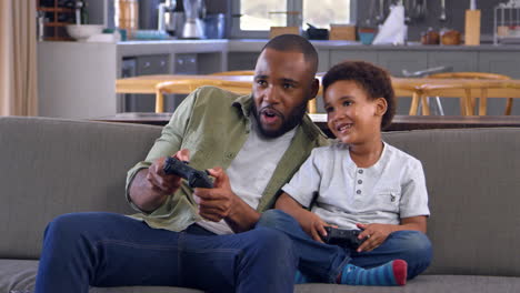 Vater-Und-Sohn-Sitzen-Auf-Dem-Sofa-In-Der-Lounge-Und-Spielen-Videospiel