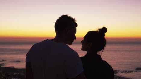 Couple-kissing-by-the-sea-at-sunset,-silhouette