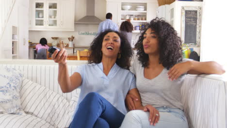 Mother-With-Teenage-Daughter-Sits-On-Sofa-Watching-TV-Together