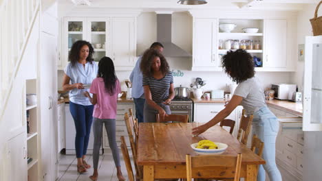Family-With-Teenage-Children-Laying-Table-For-Meal-In-Kitchen