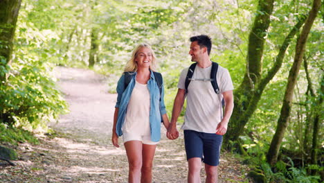 Slow-Motion-Shot-Of-Young-Couple-Hiking-Along-Woodland-Path-In-Lake-District-UK-Together