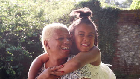 Senior-black-woman-and-granddaughter-sit-embracing-outside