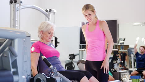 Ältere-Frau-Trainiert-Auf-Fitnessgeräten-Und-Wird-Dabei-Von-Einem-Personal-Trainer-Ermutigt