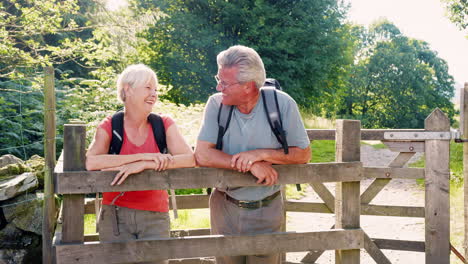 Zeitlupenporträt-Eines-älteren-Paares,-Das-Im-Britischen-Seengebiet-Wandert-Und-über-Ein-Holztor-Blickt