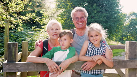 Zeitlupenporträt-Von-Großeltern-Mit-Enkelkindern-Beim-Wandern-Im-Britischen-Seengebiet-Mit-Blick-Auf-Ein-Holztor