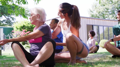 Female-Instructor-Helping-Students-At-Outdoor-Yoga-Class