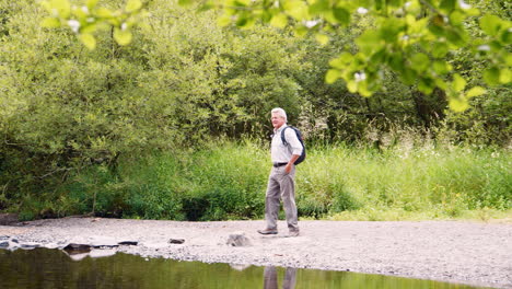 Zeitlupenaufnahme-Eines-älteren-Mannes,-Der-Beim-Wandern-Im-Britischen-Seengebiet-Trittsteine-Benutzt,-Um-Den-Fluss-Zu-überqueren