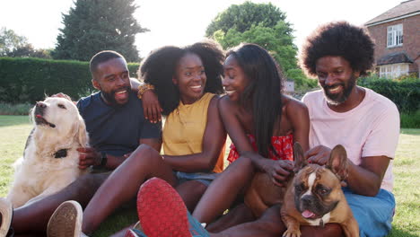 Two-black-couples-sitting-on-grass-with-their-dogs-in-Summer