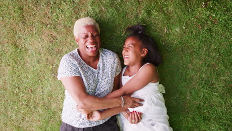 Black-girl-and-grandmother-lying-on-grass,-overhead-close-up