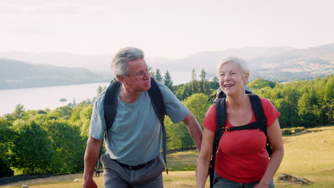 Slow-Motion-Shot-Of-Senior-Couple-Climbing-Hill-On-Hike-Through-Countryside-In-Lake-District-UK-Together