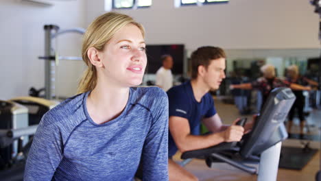 Portrait-Of-Active-Woman-Resting-After-Exercising-On-Cycling-Machines-In-Gym