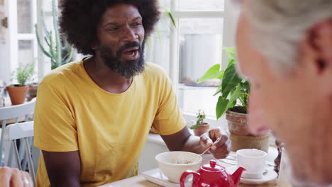 Hombre-Negro-De-Mediana-Edad-Desayunando-Con-Amigos-En-Una-Cafetería,-De-Cerca,-Enfoque-Selectivo