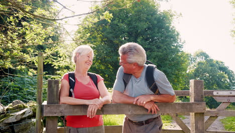 Zeitlupenporträt-Eines-älteren-Paares,-Das-Im-Britischen-Seengebiet-Wandert-Und-über-Ein-Holztor-Blickt