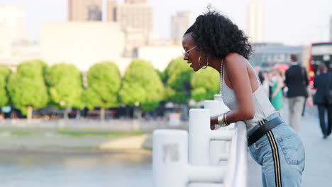 Young-black-woman-admiring-the-view-from-a--bridge-in-the-city,-side-view