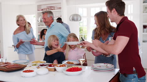 Slow-Motion-Shot-Of-Multi-Generation-Family-And-Friends-Gathering-In-Kitchen-For-Celebration-Party