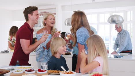 Slow-Motion-Shot-Of-Multi-Generation-Family-And-Friends-Gathering-In-Kitchen-For-Celebration-Party