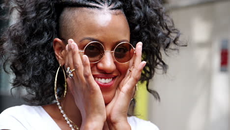 Happy-young-black-woman-playing-with-her-sunglasses-and-laughing,-close-up