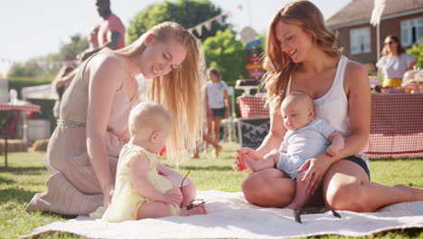 Slow-Motion-Shot-Of-Two-Mothers-Sitting-On-Rug-And-Playing-With-Babies-At-Summer-Garden-Fete