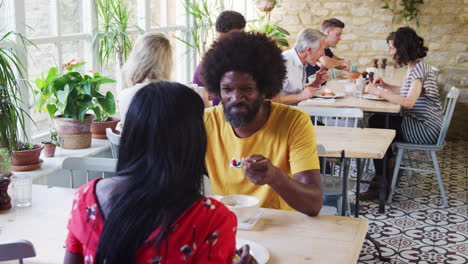 Black-adult-couple-talking-over-brunch-in-a-busy-restaurant,-close-up