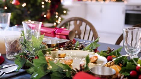 A-dining-table-prepared-for-Christmas-dinner,-with-a-Christmas-tree-and-kitchen-background,-camera-pans-along-the-table