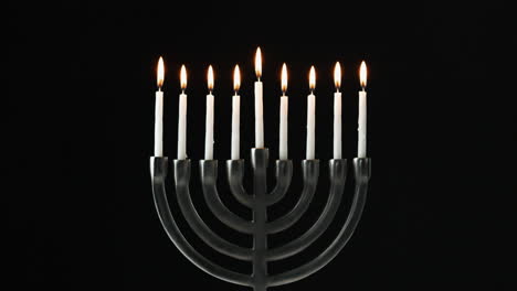 A-row-of-nine-white-candles-burning-in-a-menorah-are-blown-out,-front-view