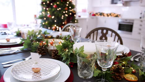 A-close-up,-slow-panning-shot-showing-a-festive-Christmas-dining-table-with-bauble-name-card-holders-arranged-on-plates-and-green-and-red-seasonal-decorations