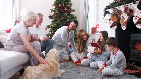 Drei-Generationen-Familie-Trägt-Pyjamas-In-Der-Lounge-Zu-Hause-Und-öffnet-Geschenke-Am-Weihnachtstag