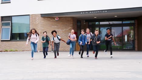 Group-Of-High-School-Students-Running-Out-Of-School-Buildings-Towards-Camera-At-The-End-Of-Class