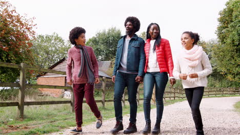 Mixed-race-family-walking-together-on-a-countryside,-children-running-ahead-of-their-parents,-low-angle