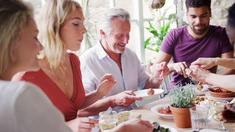 Eine-Gemischte-Altersgruppe-Erwachsener-Freunde,-Die-Gemeinsam-Tapas-An-Einem-Tisch-In-Einem-Restaurant-Essen,-Selektiver-Fokus
