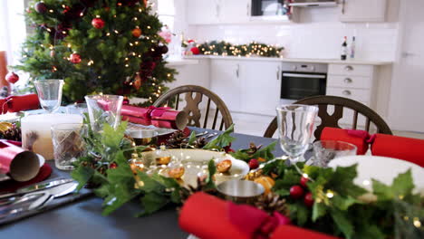 Ein-Dekorierter-Weihnachtstisch-Mit-Auf-Tellern-Arrangierten-Weihnachtscrackern-In-Einem-Esszimmer,-Mit-Einem-Weihnachtsbaum-Und-Einer-Küche-Im-Hintergrund