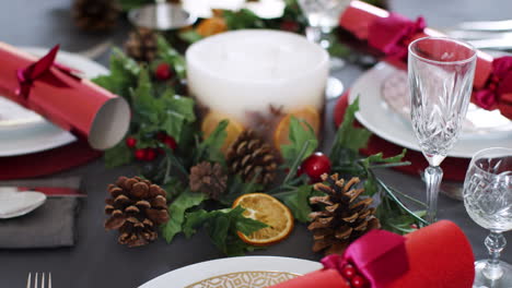 Nahaufnahme-Eines-Weihnachtlichen-Esstisches-Mit-Saisonalen-Dekorationen,-Kristallgläsern-Und-Weihnachtsknallbonbons-Auf-Tellern