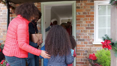 Grandparents-Greeting-Family-As-They-Arrive-For-Visit-On-Christmas-Day-With-Gifts
