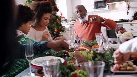 Black-multi-generation-family-serving-themselves-food-at-their-Christmas-dinner-table