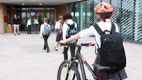 Group-Of-High-School-Students-Wearing-Uniform-Arriving-At-School-Walking-Or-Riding-Bikes
