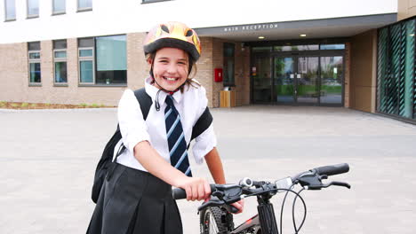 Portrait-Of-Female-High-School-Student-Wearing-Uniform-With-Bicycle-Outside-School-Buildings