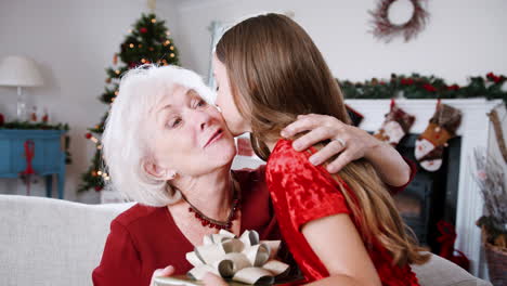 Grandmother-Receiving-Christmas-Gift-From-Granddaughter-At-Home