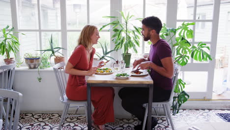 Young-adult-couple-talking-having-lunch-together-in-an-empty-restaurant,-full-view