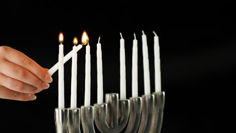 Hand-lighting-the-nine-white-candles-in-a-Jewish-menorah-sat-on-a-pale-marble-surface,-side-view,-close-up-detail