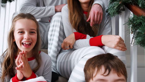 Porträt-Einer-Aufgeregten-Familie-Im-Schlafanzug,-Die-Am-Weihnachtsmorgen-Auf-Der-Treppe-Sitzt