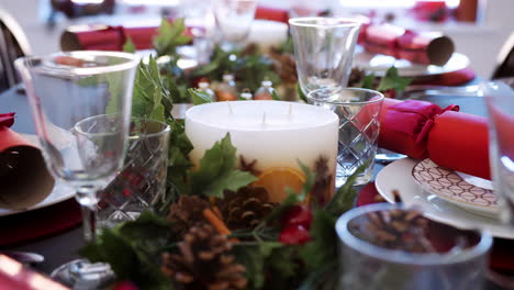 Tilt-shot-of-a-white-candle-on-a-dining-table-decorated-in-preparation-for-Christmas-dinner,-detail,-selective-focus
