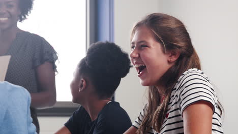 High-School-Teacher-And-Students-Laughing-During-Lesson-In-Classroom