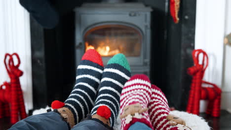 Close-Up-Of-Senior-Couple-Wearing-Christmas-Socks-Warming-Feet-On-Wood-Burning-Stove