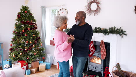 Senior-black-couple-dancing-in-their-living-room,-decorated-for-Christmas,-three-quarter-length-view,-handheld