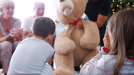 Children-Playing-With-Giant-Teddy-Bear-As-Multi-Generation-Family-Open-Gifts-On-Christmas-Day