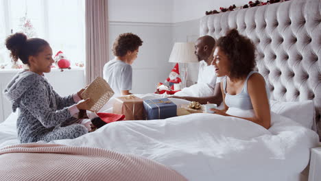 Aufgeregte-Kinder-Laufen-In-Das-Schlafzimmer-Ihrer-Eltern-Und-Springen-Mit-Weihnachtsstrümpfen-Und-Geschenken-Auf-Ihr-Bett-Am-Weihnachtsmorgen,-Seitenansicht