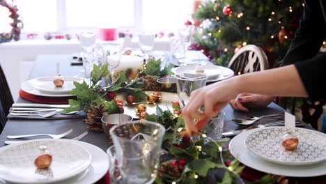 A-woman-adjusting-festive-decorations-on-a-Christmas-dinner-table,-detail-shot-of-hands,-elevated-view