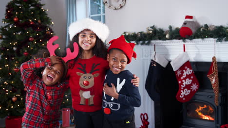 Porträt-Von-Kindern,-Die-Festliche-Pullover-Und-Hüte-Tragen-Und-Gemeinsam-Weihnachten-Zu-Hause-Feiern