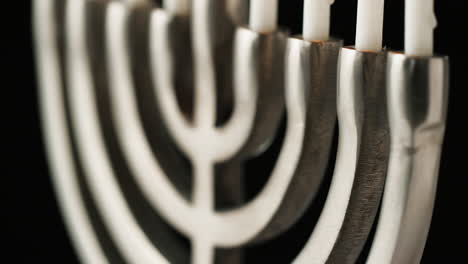 Close-up,-shallow-depth-of-field-tilt-shot-of-silver-menorah-at-an-angle,-with-white-lit-candles