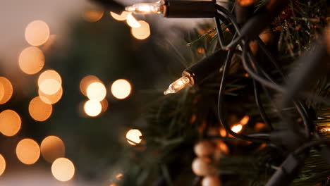 Rack-focus-close-up-of-glittering-baubles-hanging-on-a-Christmas-tree-with-fairy-lights,-bokeh